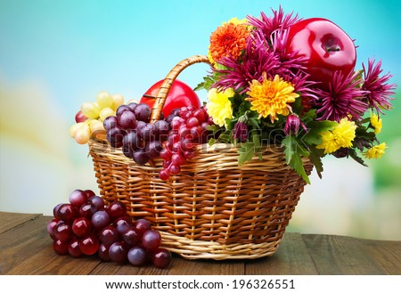 Composition with beautiful flowers in wicker basket and fruits,  on bright background