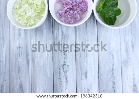 Aromatherapy treatment bowls with flowers and perfumed water on wooden background