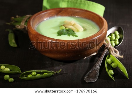 Tasty peas soup on wooden table with dark light