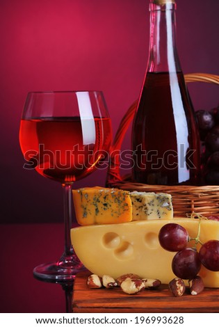 Pink wine, grapes and cheese on colorful background