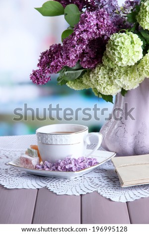 Composition with  cup of tea, old letters and beautiful spring flowers in vase, on wooden table, on bright background