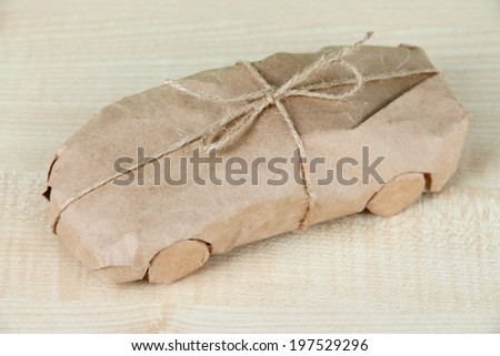 Car wrapped in brown kraft paper, on wooden background
