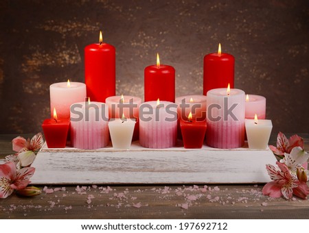 Beautiful candles with flowers on table on brown background