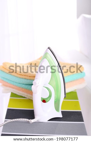 Clean clothes and iron on ironing board on light background
