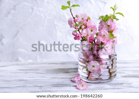 Beautiful fruit blossom in jar on table on grey background