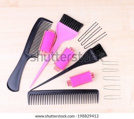 Professional hairdresser tools - comb, scissors, pins and curlers on light wooden background