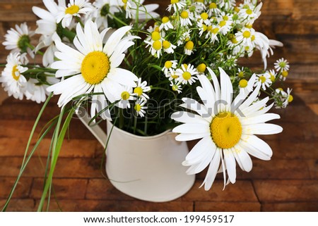 Beautiful bouquet of daisies in decorative vase on wooden background