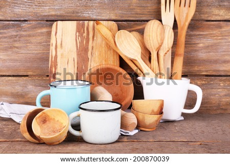Composition of wooden cutlery, pan, bowl and cutting board on wooden background