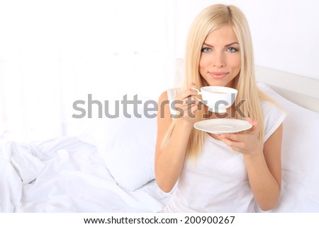 Young beautiful woman with cup of tea in bed