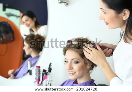 Young woman hairdresser do hairstyle girl in beauty salon