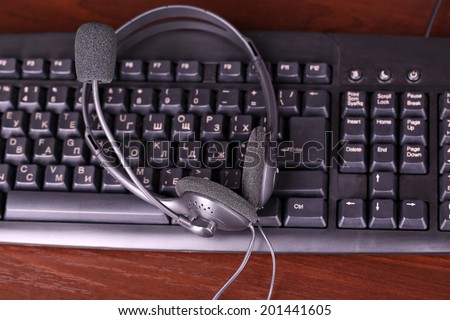 Headphone and keyboard close-up on wooden desk background