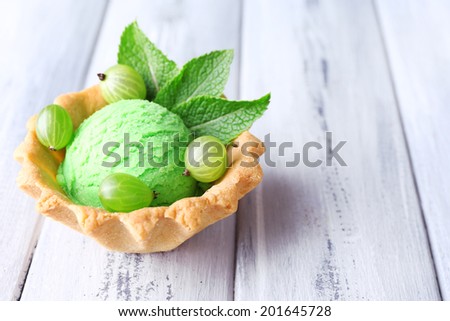 Green ice cream  ball in wafer bowl on color wooden background