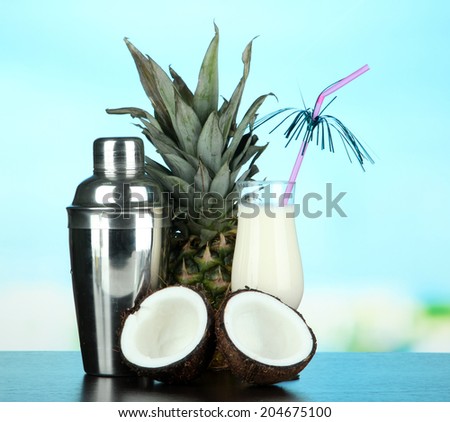 Pina colada drink in cocktail glass and metal shaker, on bright background
