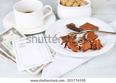 Check, money and remnants of food and drink on table close-up
