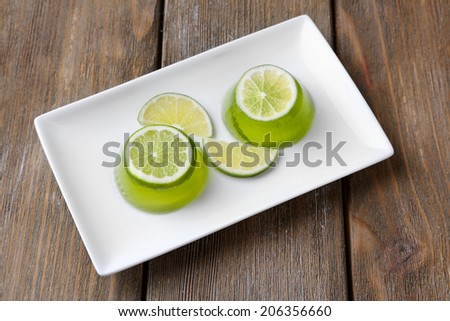 Green jelly with lemon lime slices on wooden background