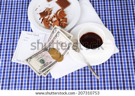 Check, money and remnants of food and drink on table close-up