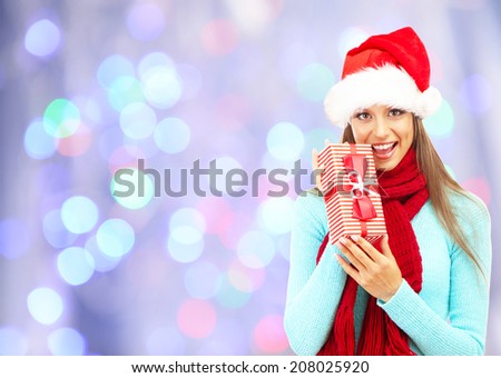 Beautiful young woman with gift on bright background