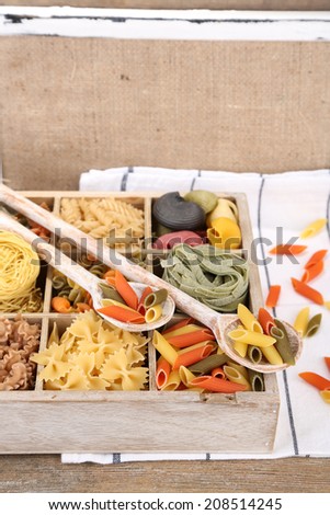Colorful pasta in wooden box on wooden table background