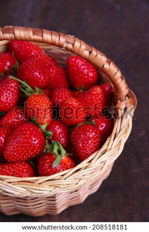 Ripe sweet strawberries in wicker basket on wooden background - stock photo
