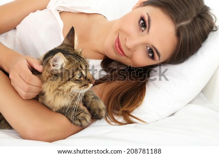 Beautiful young woman with cat resting on bed