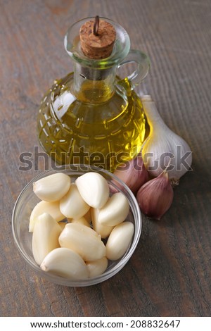 Fresh sliced garlic in glass bowl and oil in glass bottle, on wooden background