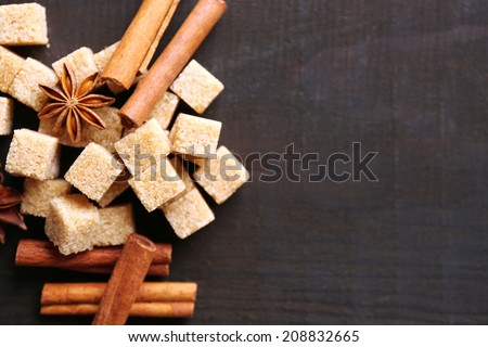 Brown sugar cubes and reed sugar, spices on wooden background