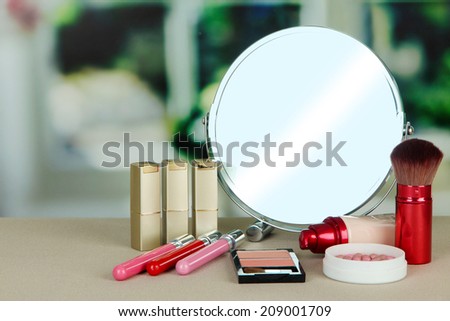 Round table mirror with cosmetics on table on bright background