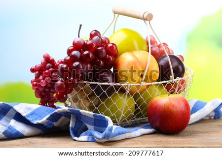 Assortment of juicy fruits in wicker basket on table, on bright background