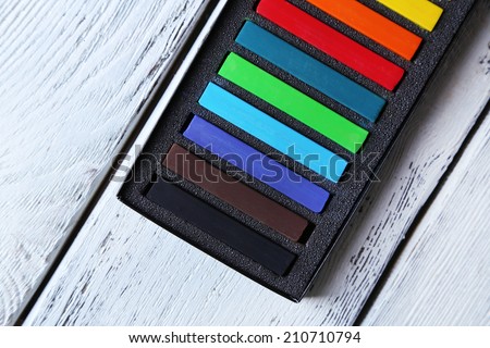 Colorful chalk pastels in box on wooden background
