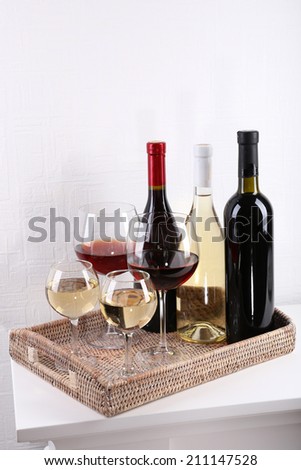 Bottles and glasses of wine on table in room