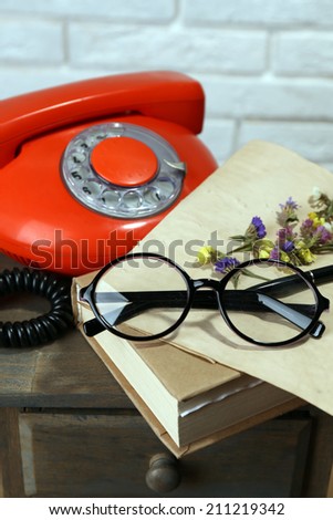 Retro phone, book and glasses on table in room