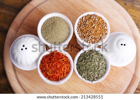 Small round tea bowls with different seasoning on a wooden round tray on wooden background