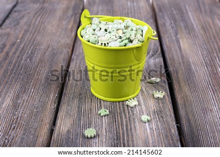 Beads in metal bucket on wooden background