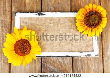 Beautiful sunflowers with frame on wooden background