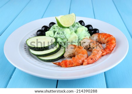 Fresh prawns with avocado, olives, salad and lime on blue wooden background