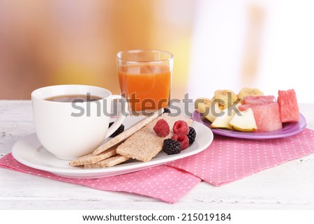 Slices of fruits with crispbreads and cup of tea on table on bright background
