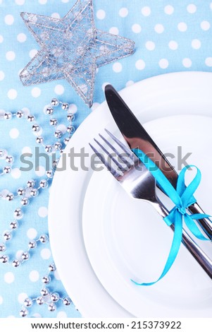 White plate, fork, knife and Christmas decoration on polka dot tablecloth closeup
