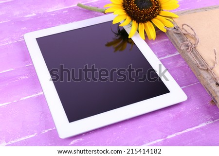 Tablet, notebook and sunflower on wooden background