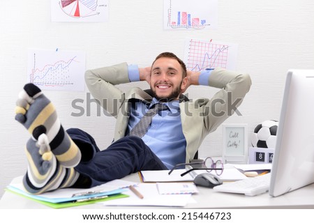 Confident businessman holding his legs in funny socks on desk