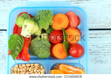 Tasty vegetarian food in plastic box on wooden table