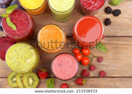 Glasses of tasty fresh juice, on wooden table.