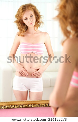 Beautiful woman with slim body posing near mirror in room