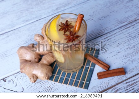Glass of ginger drink with lemon on bamboo napkin on wooden background