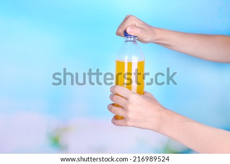 Hand opening bottle with sweet water on sky background
