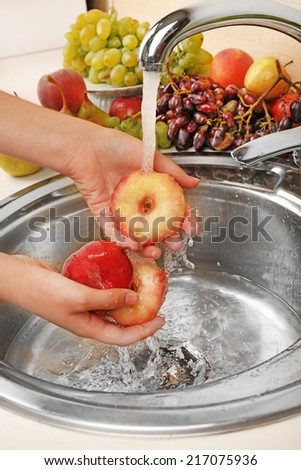 Woman\'s hands washing peaches in sink