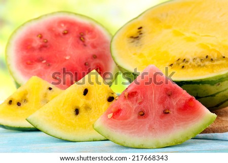 Slices of red and yellow watermelons on wooden table on natural background