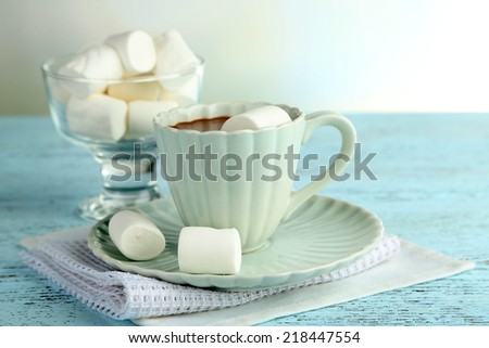 Hot chocolate with marshmallows in mug, on color wooden table, on light background