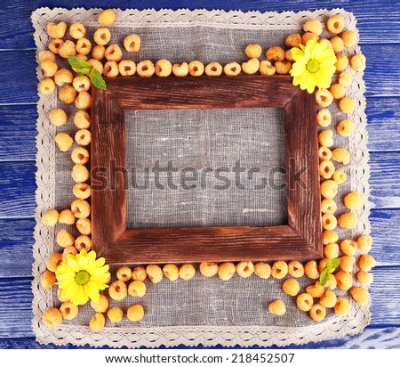 Yellow raspberries, wooden photo frame and wildflowers on sackcloth on wooden background