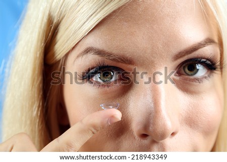 Medicine and vision concept - young woman with contact lens, close up