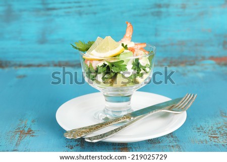 Tasty salad with shrimps and avocado, on wooden background
